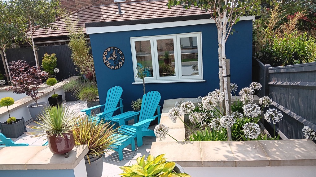A finished courtyard garden with sandstone raised beds, a porcelain patio and a blue garden room