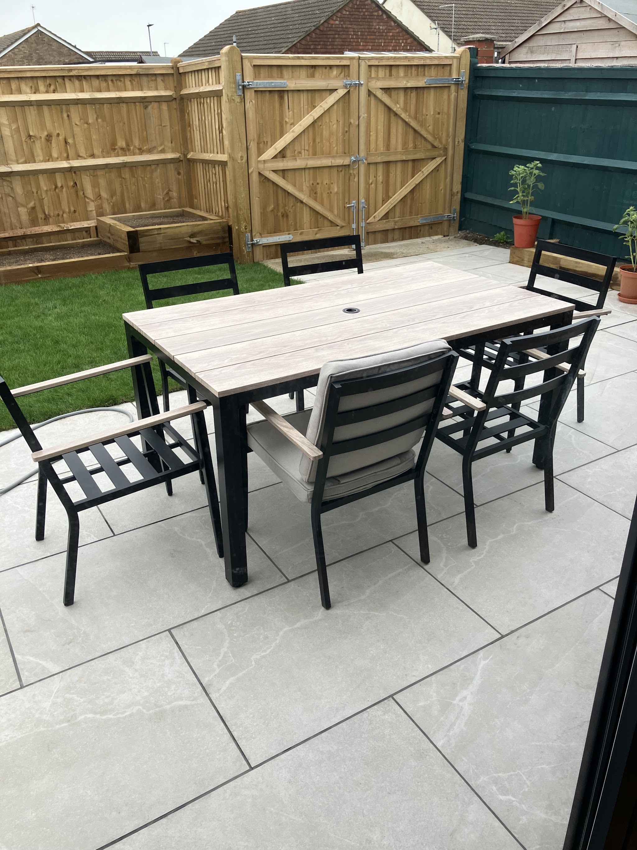 A light porcelain patio with an outdoor dining set beside a new fence