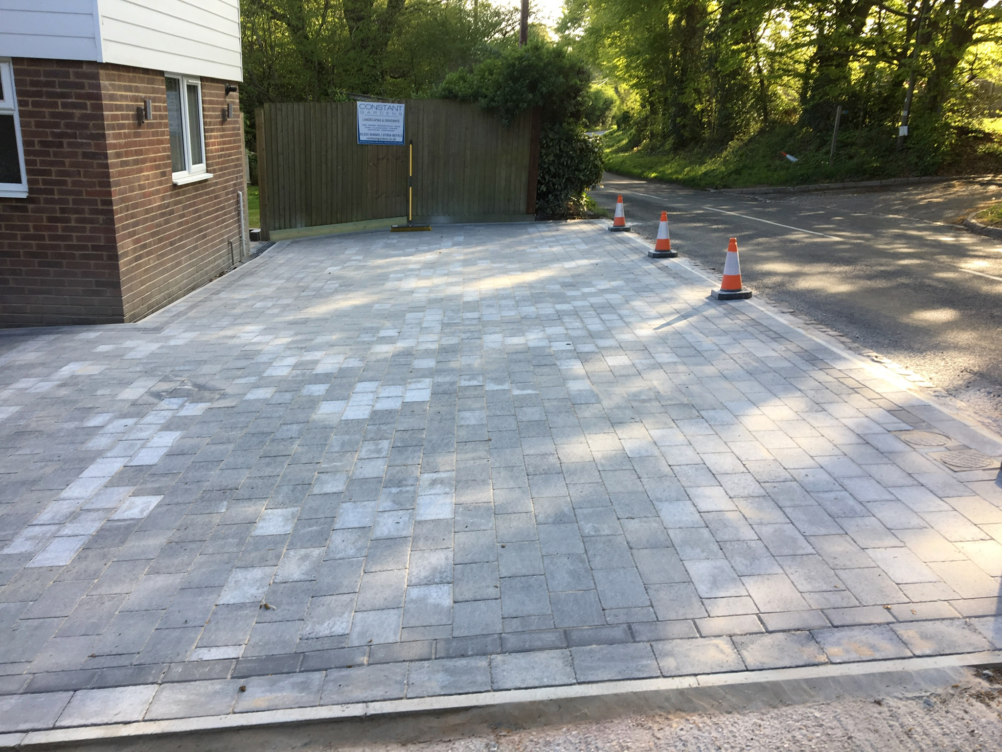 A new grey block-paved driveway leading to wooden gates
