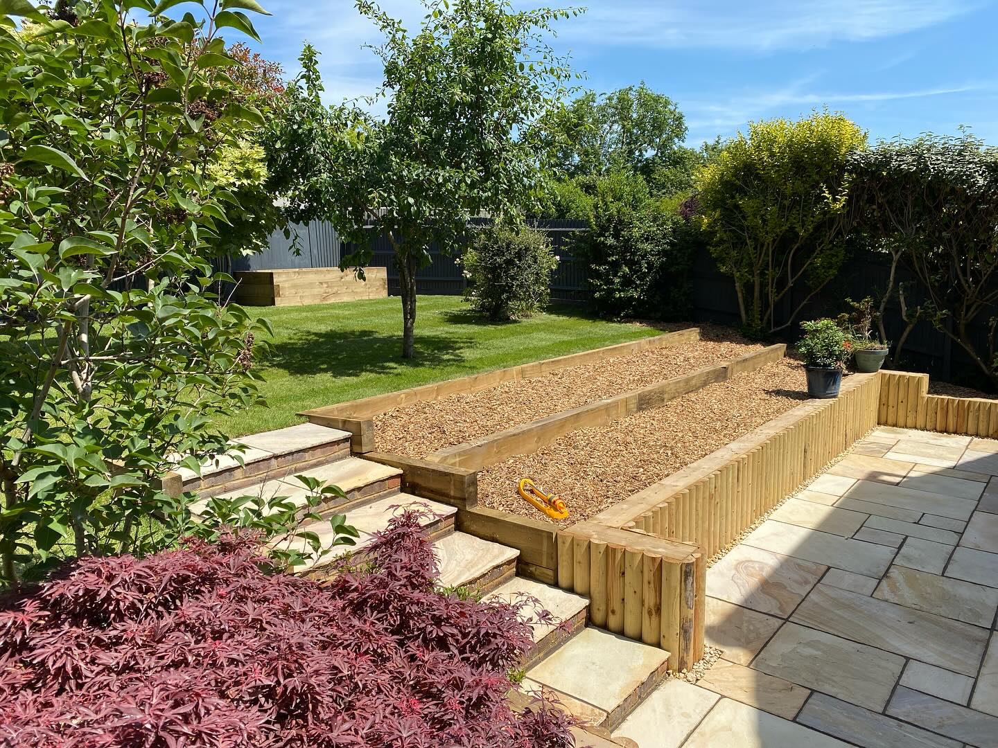 Sleeper-edged raised beds and steps beside new paving