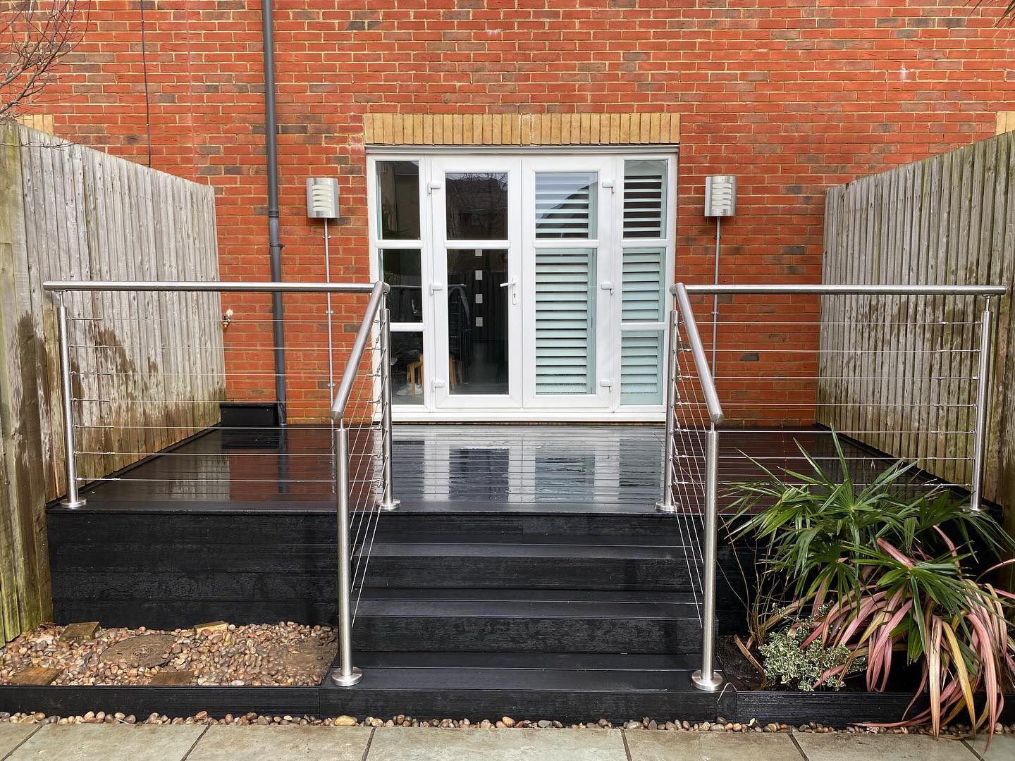Composite steps and deck with a glass and steel balustrade at French doors