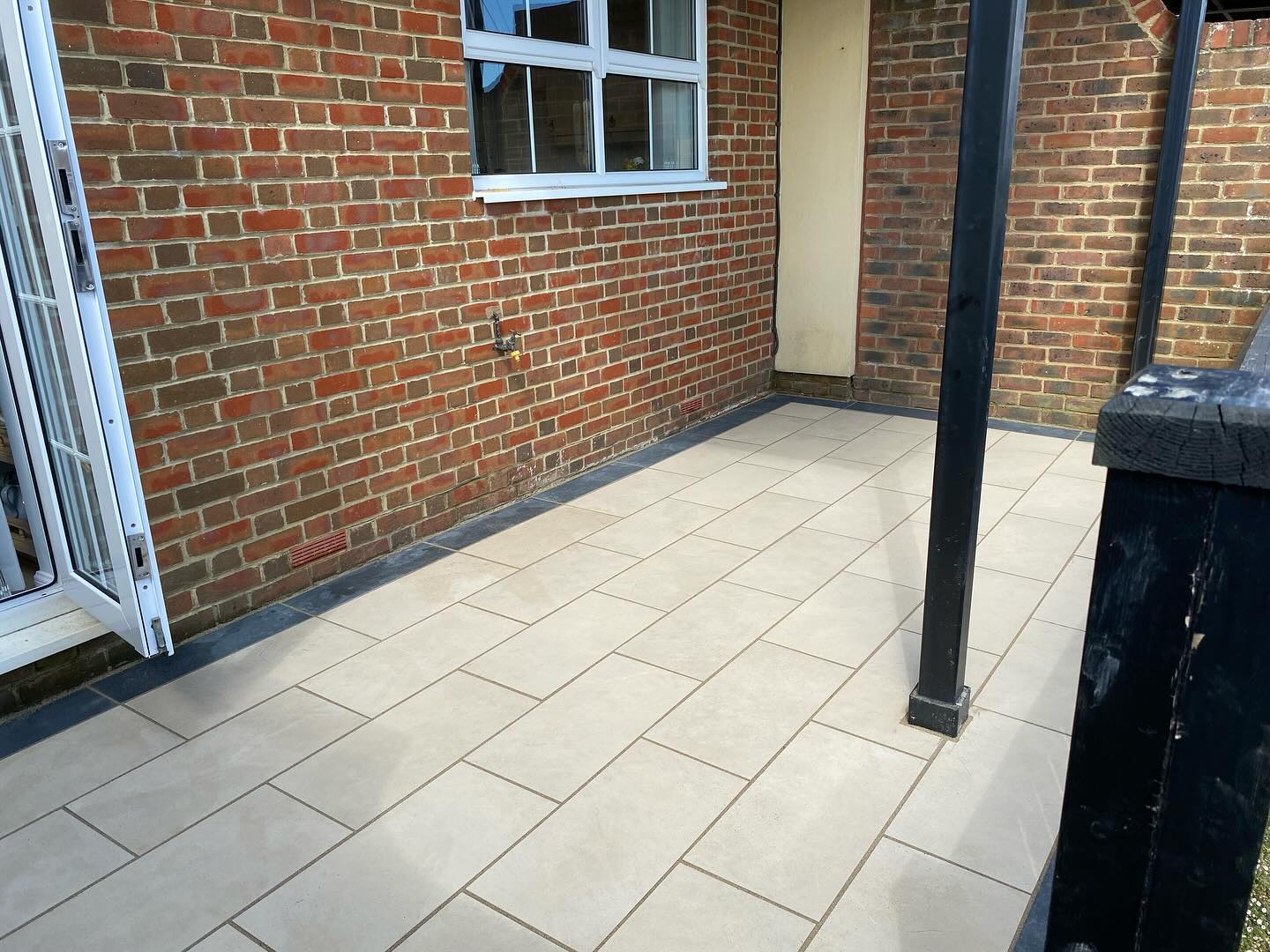 Pale paving slabs laid against a brick house wall